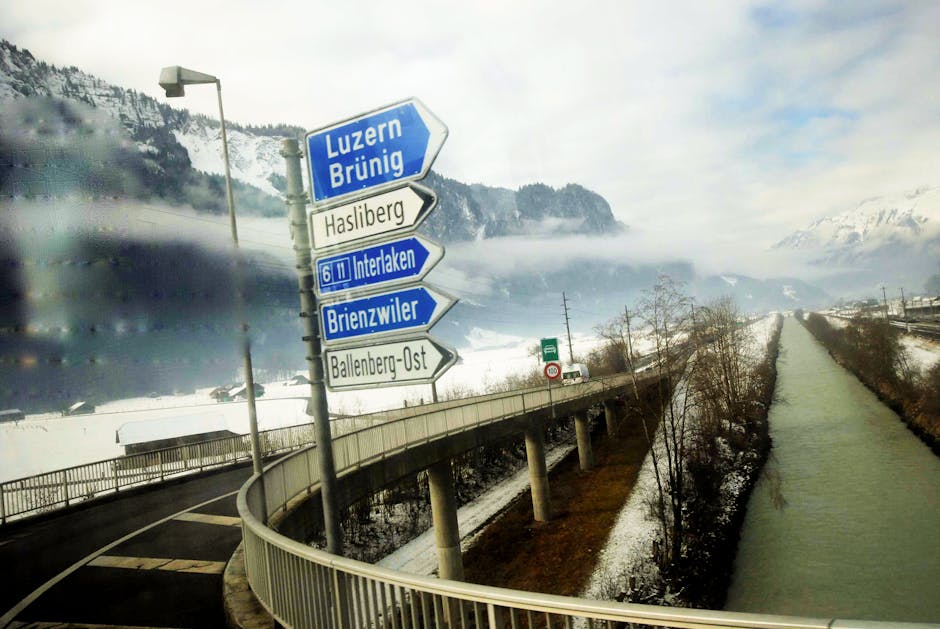 Road signs in snowy Swiss landscape with foggy mountains in the background. Captured near Sachseln, Switzerland.