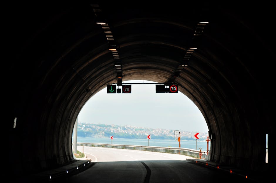 View from inside a tunnel opening to a scenic city landscape with clear skies.