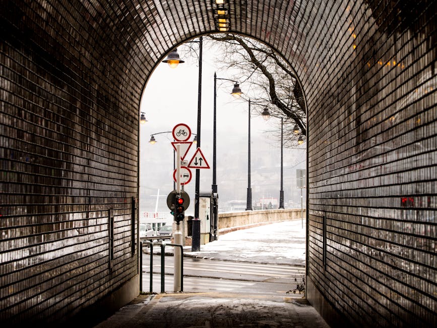 Atmospheric view through a brick tunnel to snowy street with road signs.